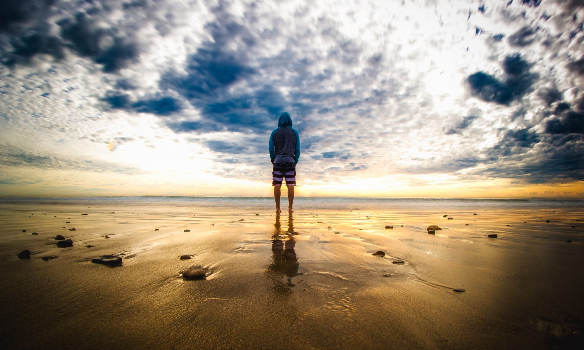 person standing on a beach during sunrise